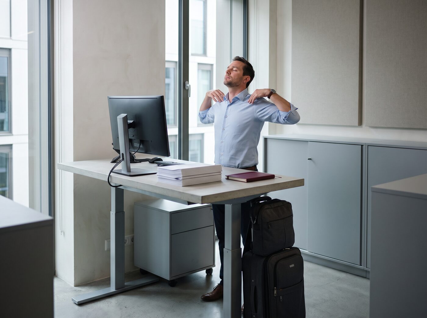 A man rolling his shoulders back at a standing desk